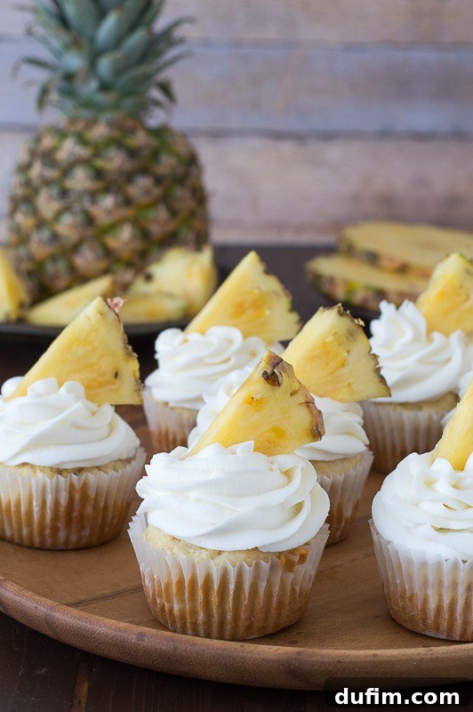 Pineapple Paradise Cupcakes 3 Close-up of a pineapple cupcake, showing the generous swirl of pineapple buttercream frosting and flecks of pineapple within the cake. The texture looks incredibly moist and appealing.