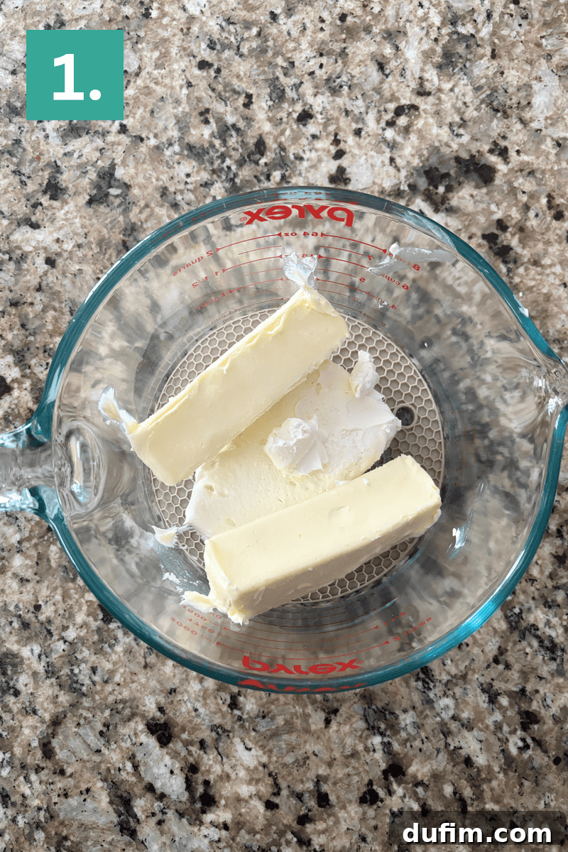 Two sticks of room-temperature butter in a clear glass measuring cup, ready for baking.