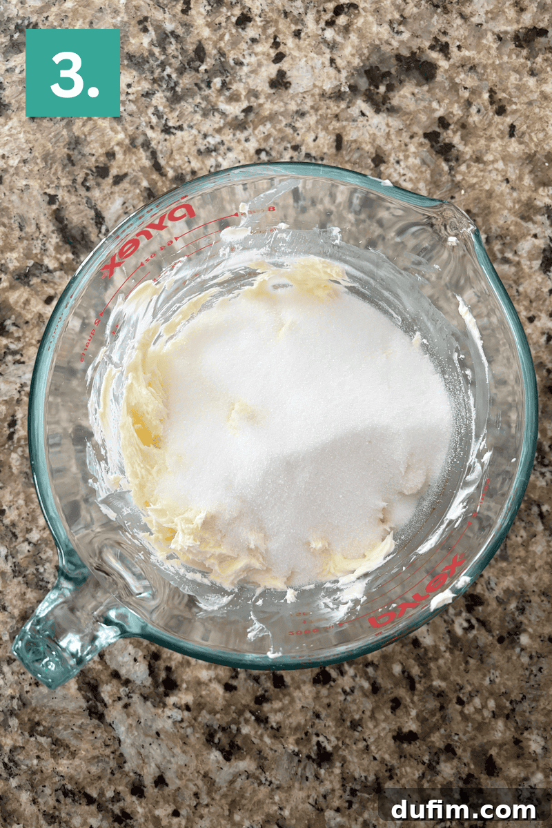 Softened butter and granulated sugar combined in a glass bowl, ready for creaming.