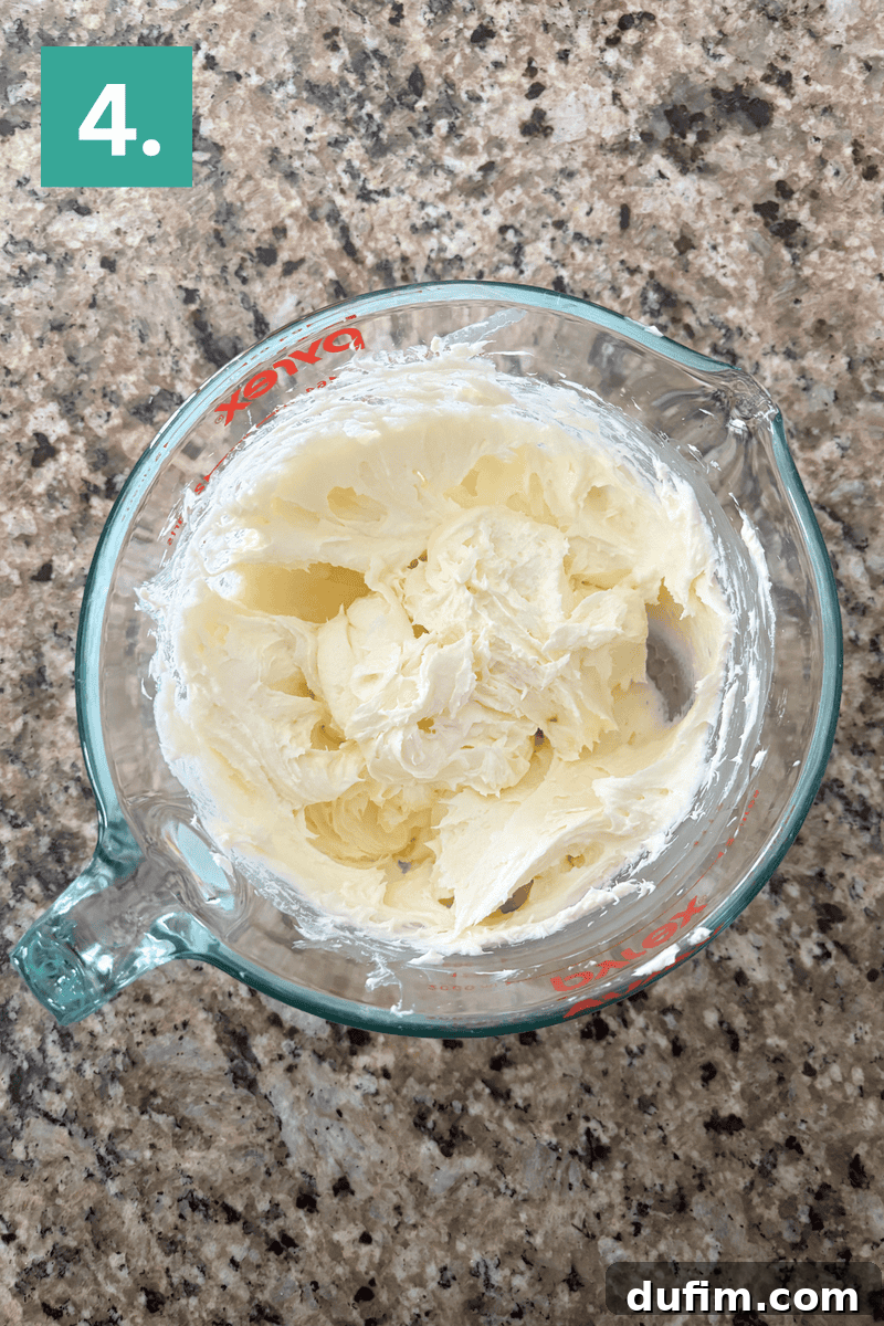 A creamy, airy mixture of butter, cream cheese, and sugar in a glass bowl after proper creaming.