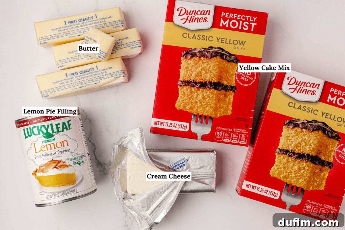 Labeled ingredients for a delightful lemon cream cheese dump cake recipe are displayed on a pristine white background. The image features three sticks of rich butter, two boxes of classic yellow cake mix, a vibrant can of lemon pie filling, and a fresh package of cream cheese, ready for baking.