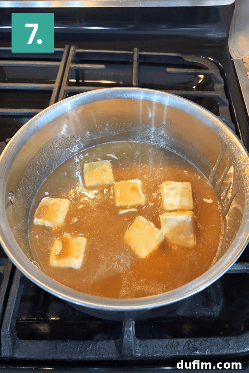 A saucepan with caramel sauce and six cubes of butter melting on a stovetop burner. A green box with the number 7 is in the top left corner of the image.