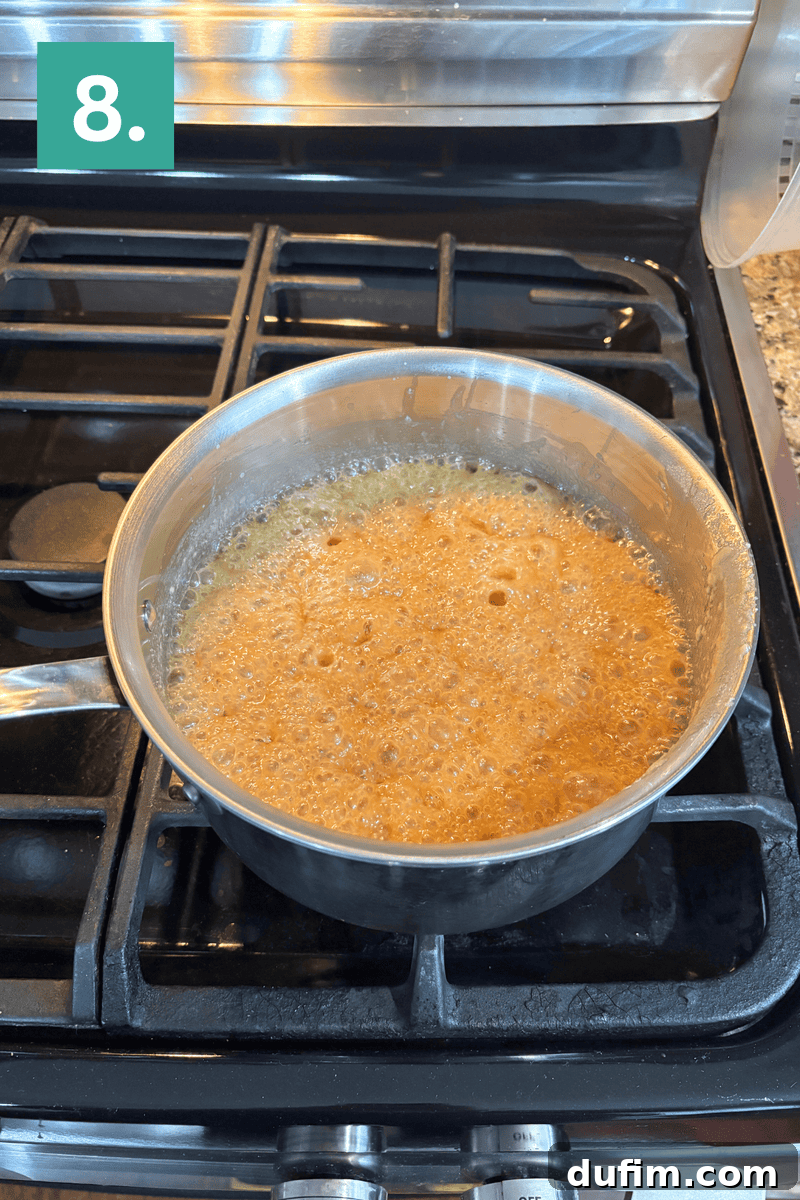 A stainless steel pot with bubbling caramel sauce cooks on a gas stove. A teal box in the upper left corner displays the number 8.
