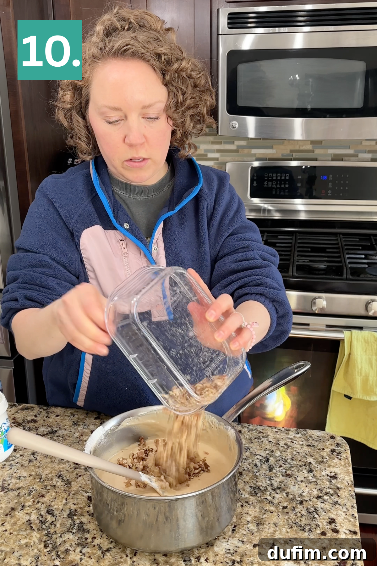 A woman pours chopped nuts from a container into a saucepan on a granite kitchen counter, with a stove and microwave in the background. A green box with the number “10.” appears in the top left corner.