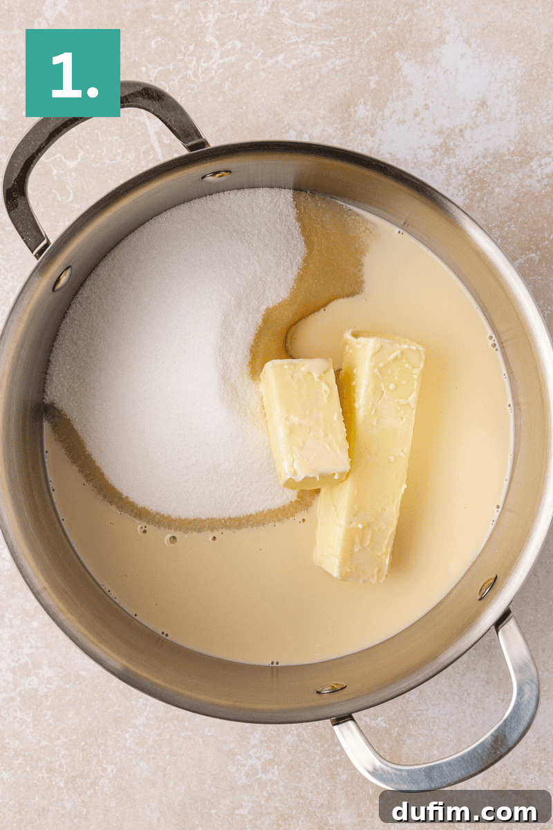 Guaranteed Perfect Vanilla Fudge 4 A metal pot containing two sticks of butter, granulated sugar, a brown liquid (possibly vanilla), and a creamy liquid, viewed from above. A green box labeled 1. is in the top left corner of the image.