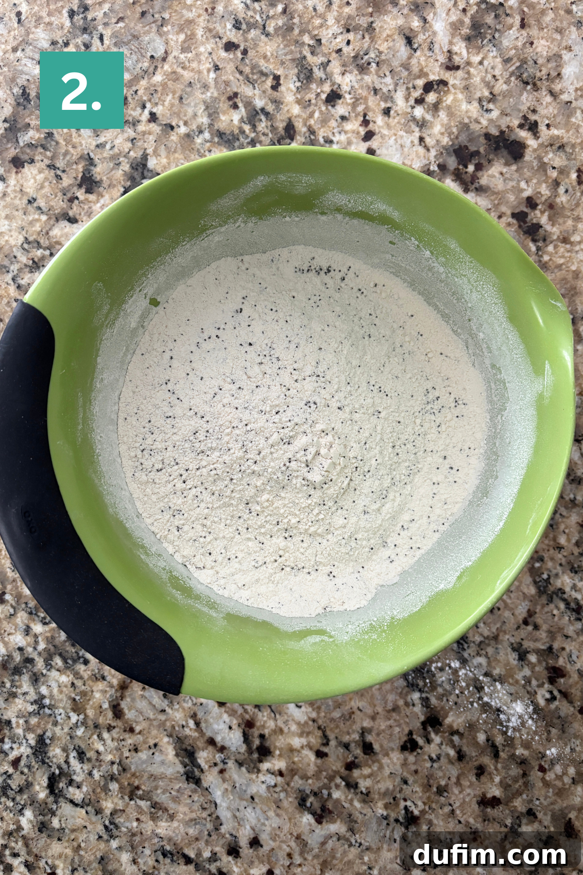 Irresistible Almond Poppy Seed Muffins 6 A closer view of the dry ingredients in a green mixing bowl, showing the flour, sugar, baking powder, salt, and poppy seeds thoroughly whisked together to ensure even distribution.