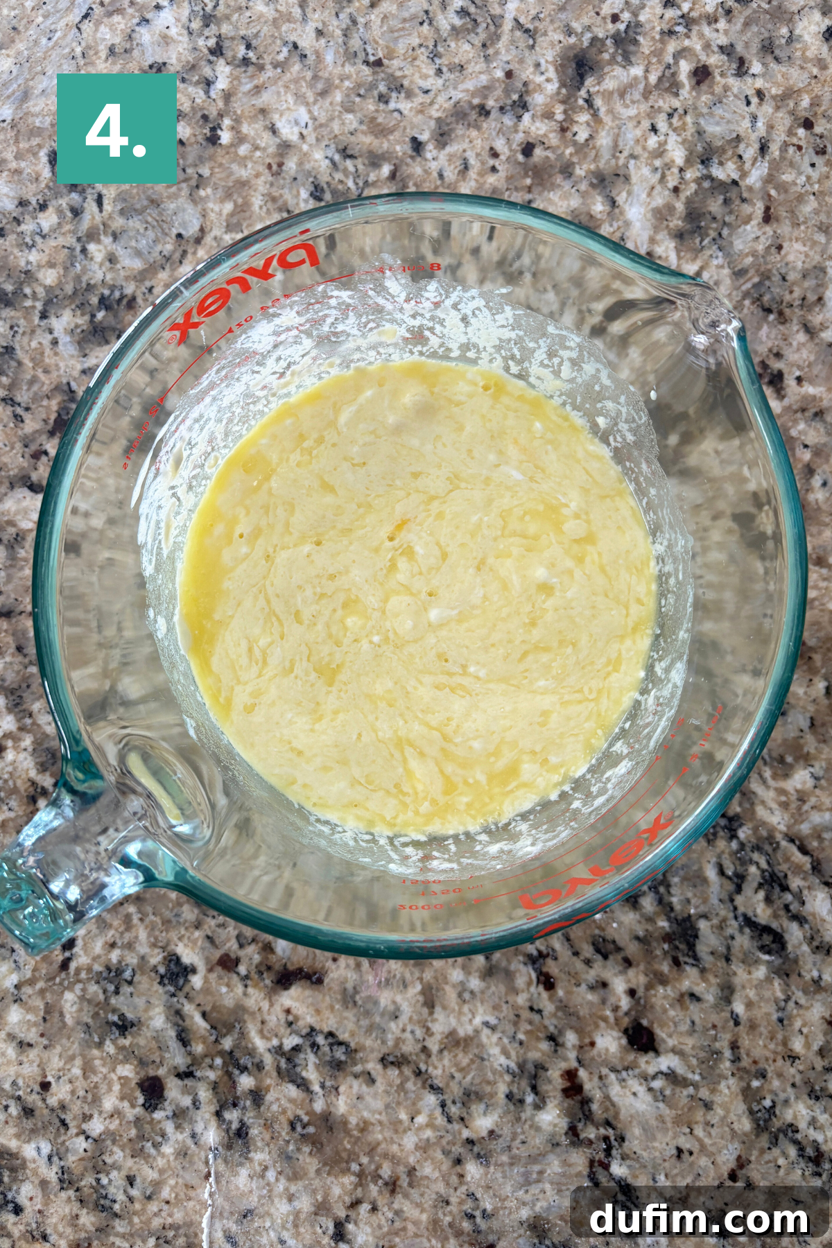 Irresistible Almond Poppy Seed Muffins 8 The liquid wet ingredients are smoothly combined in a glass measuring cup, forming a homogenous yellow mixture with a spatula.