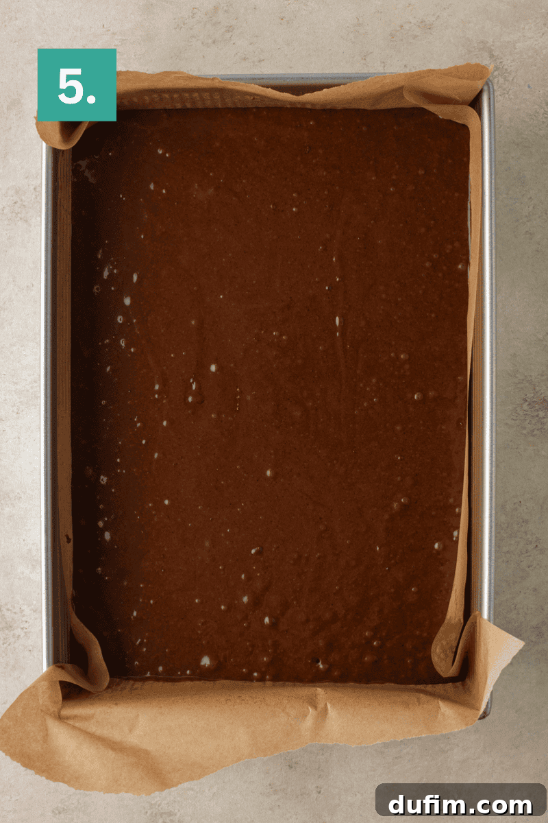 Decadent Homemade 9x13 Chocolate Cake 10 The finished chocolate cake batter poured evenly into a parchment-lined 9x13 baking pan, ready for the oven.