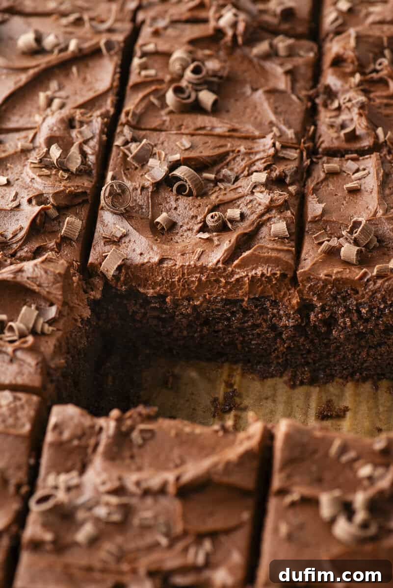 Decadent Homemade 9x13 Chocolate Cake 12 A 9x13 pan of chocolate cake covered in thick, rich chocolate frosting and cut into squares, with one slice removed to show the moist interior.