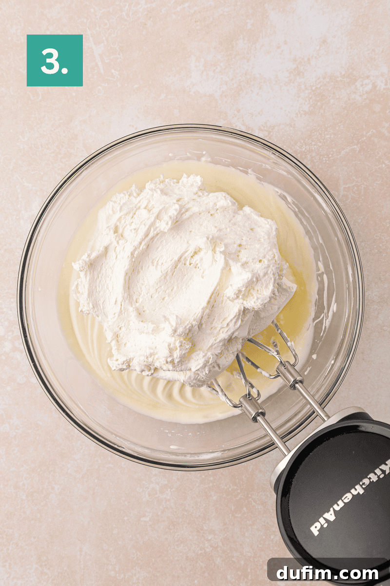 Cream Cheese Fruit Dip Recipe for Parties and Snacks 7 A glass bowl with whipped cream being mixed, seen from above.