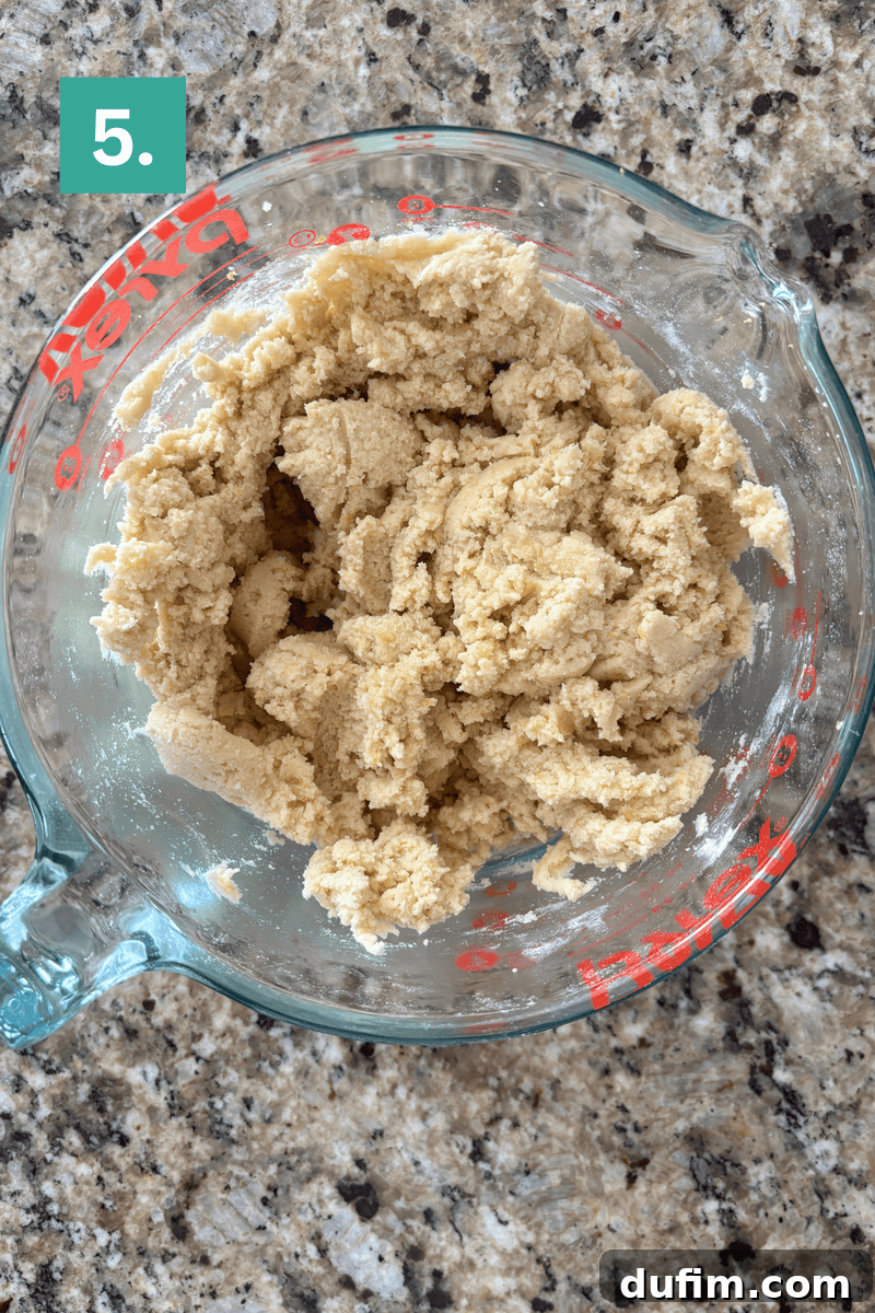 A glass bowl filled with cookie dough on a countertop.