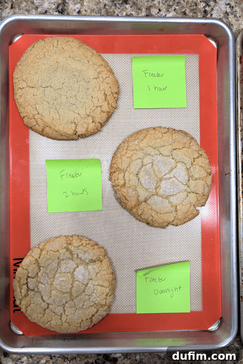 A baking tray with four large cookies on a silicone mat, each labeled with a green sticky note.