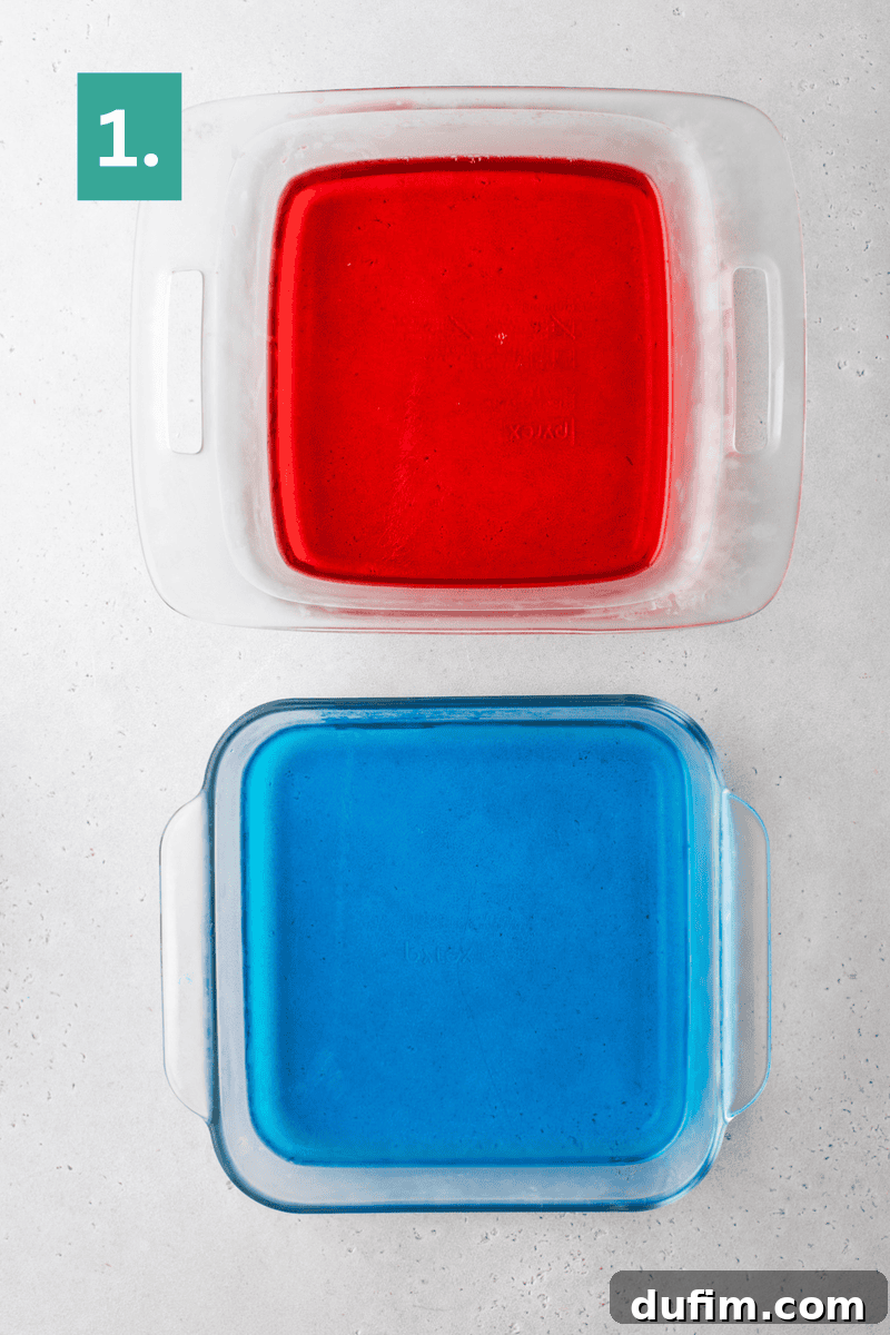 Two square glass baking dishes sit on a light surface. The top dish contains red gelatin, and the bottom dish contains blue gelatin.