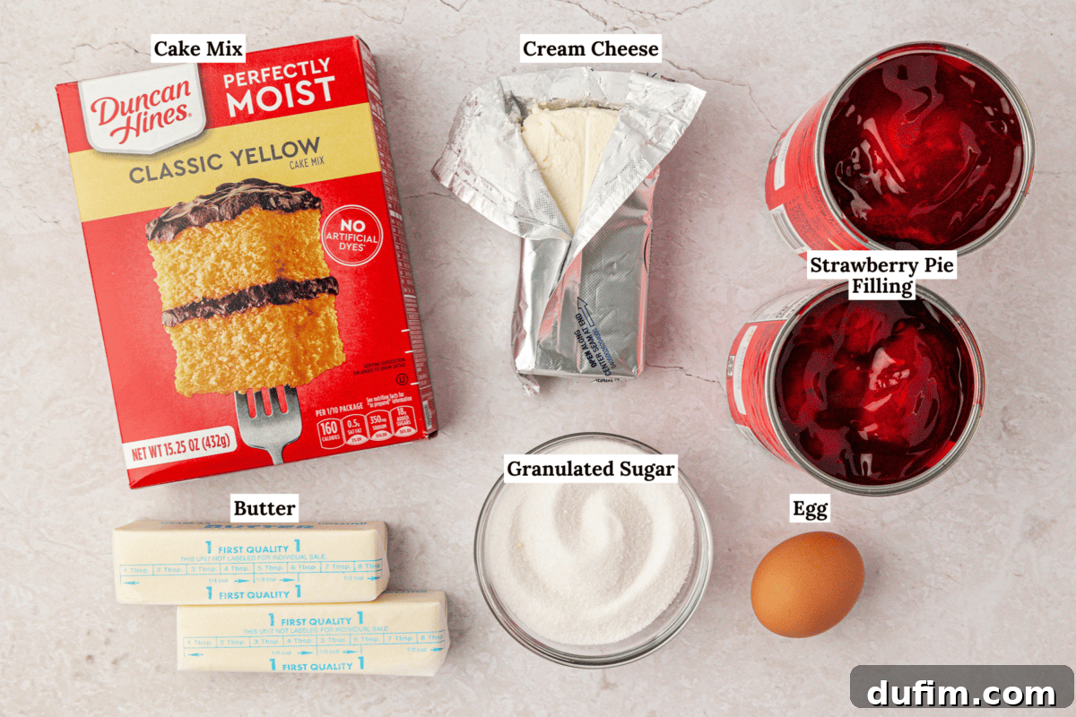 Labeled ingredients for a dessert: yellow cake mix, cream cheese, strawberry pie filling, two butter sticks, granulated sugar in a bowl, and an egg arranged on a light surface.