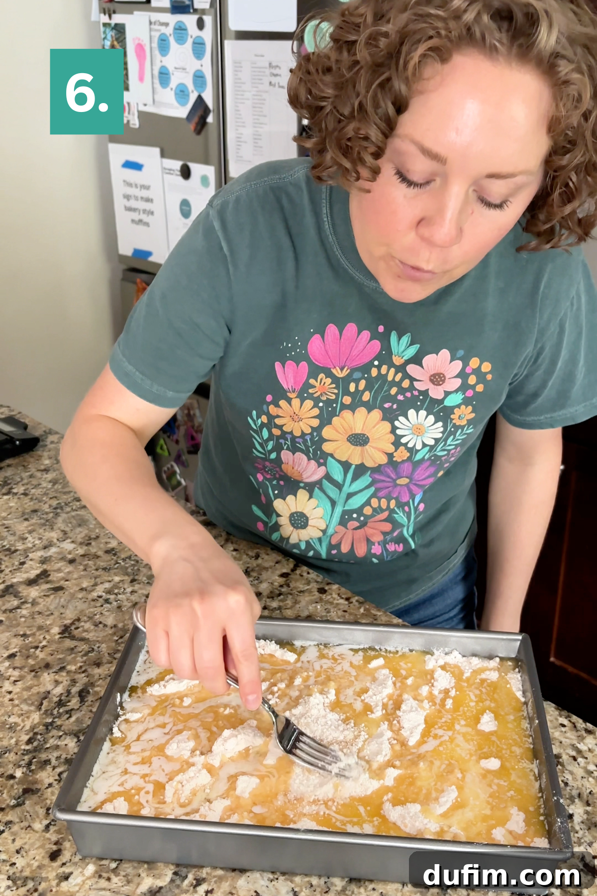 A person uses a fork to mix powdered ingredients into a yellow mixture in a baking pan.