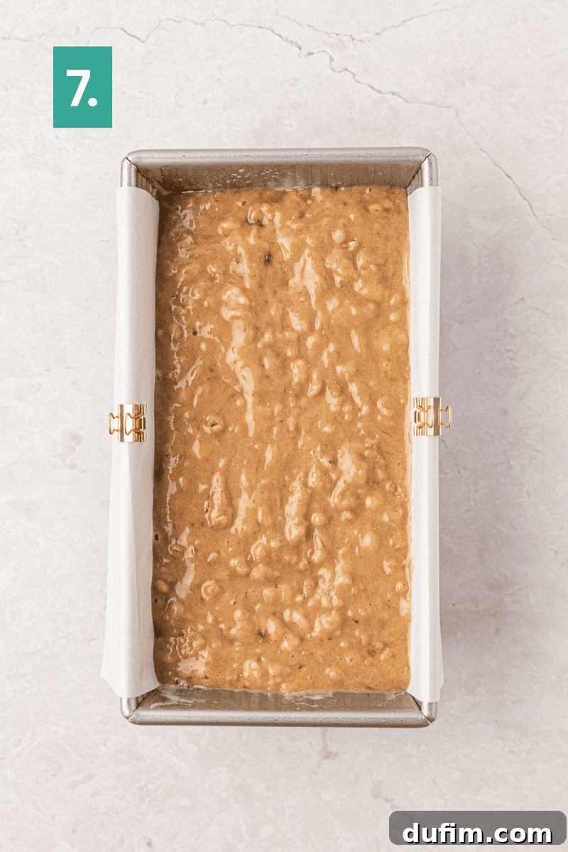 Moist Gluten-Free Banana Bread Recipe 12 A metal loaf pan lined with parchment paper is filled with banana bread batter.