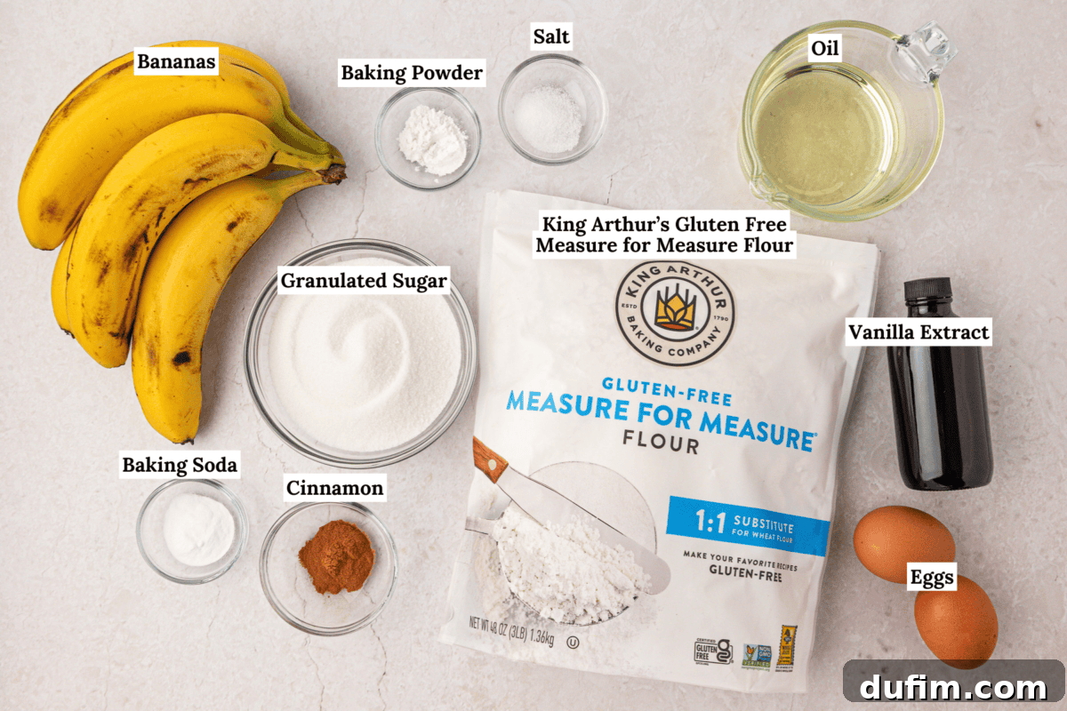 Moist Gluten-Free Banana Bread Recipe 3 A flat lay of banana bread ingredients: bananas, gluten free flour, sugar, eggs, oil, vanilla, cinnamon, baking soda, baking powder, and salt, each in bowls or containers on a white surface.