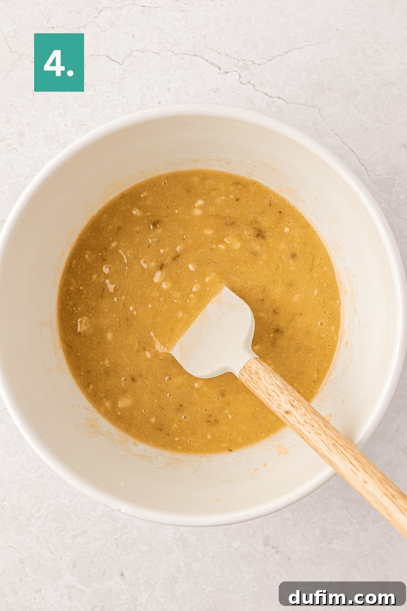 Moist Gluten-Free Banana Bread Recipe 9 A white mixing bowl with a banana bread batter and a spatula inside.