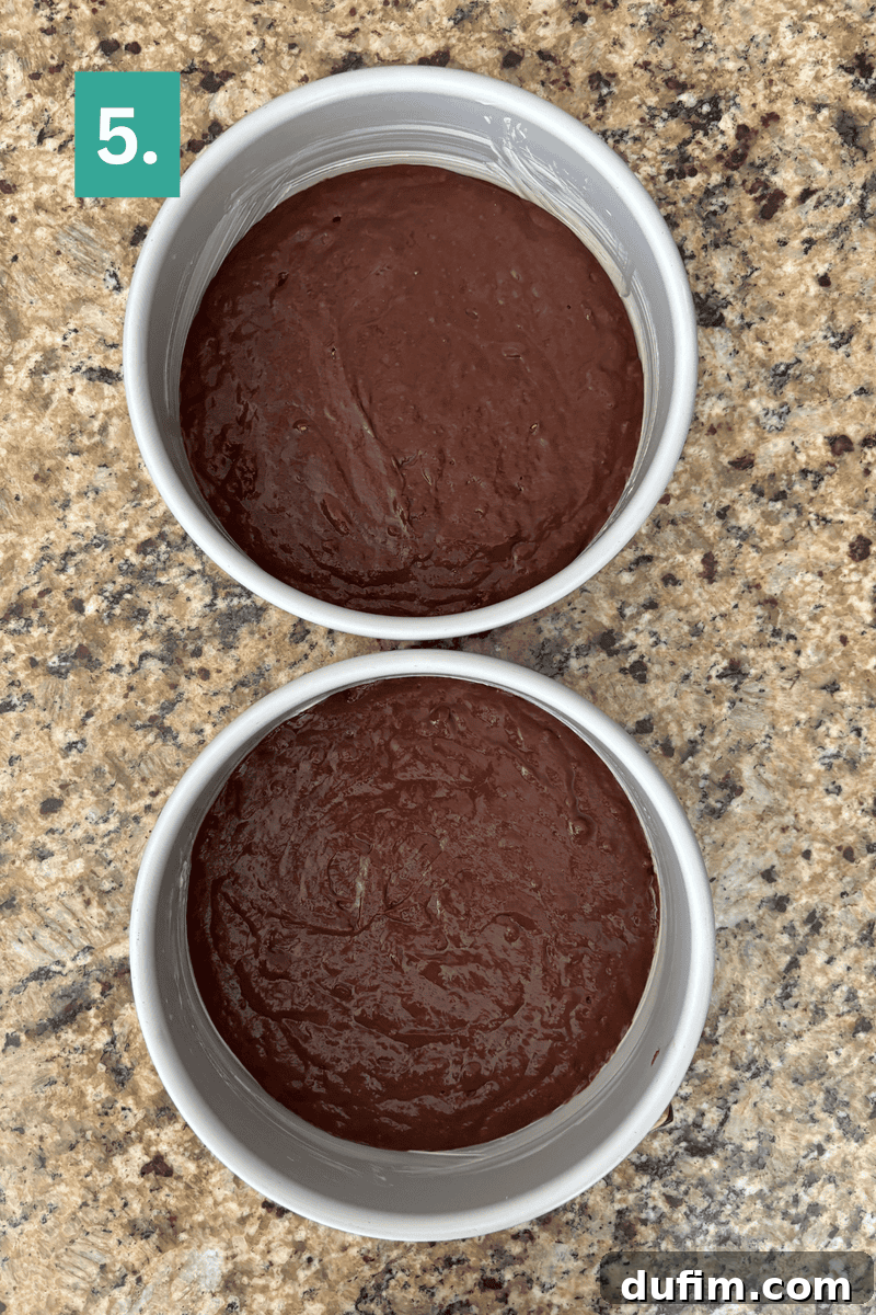 Decadent Mocha Cake Recipe for Coffee Lovers 11 Two round cake pans filled with chocolate batter are placed on a speckled countertop. A green box in the top left corner displays the number 5 in white.