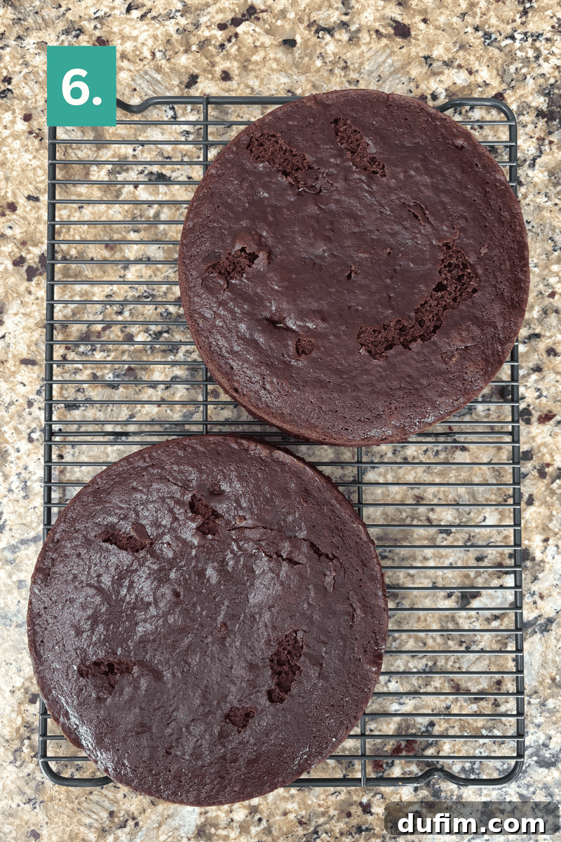Decadent Mocha Cake Recipe for Coffee Lovers 12 Two round chocolate cake layers cool on a wire rack on a granite countertop. The top layer has some cracks and holes. A green box with the number 6 is in the top left corner.